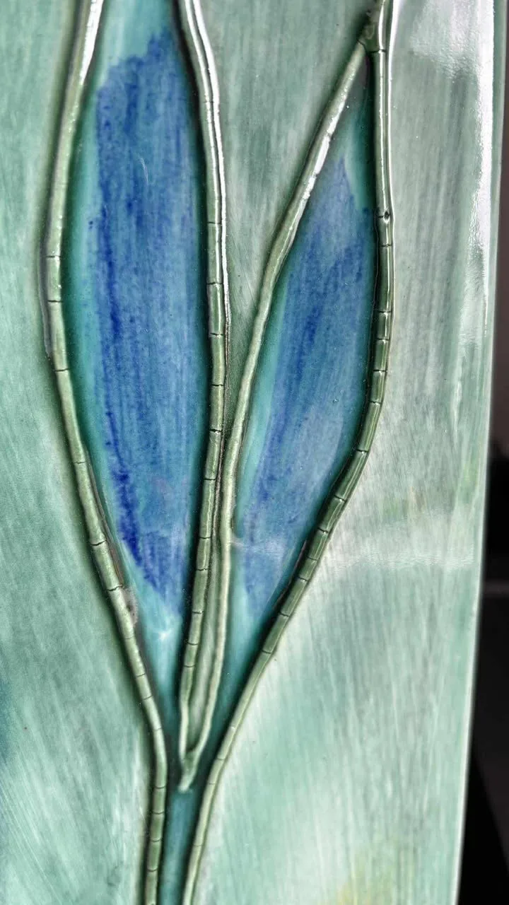 Close up of a wall panel where the glaze has lifted and cracked around a leaf motif
