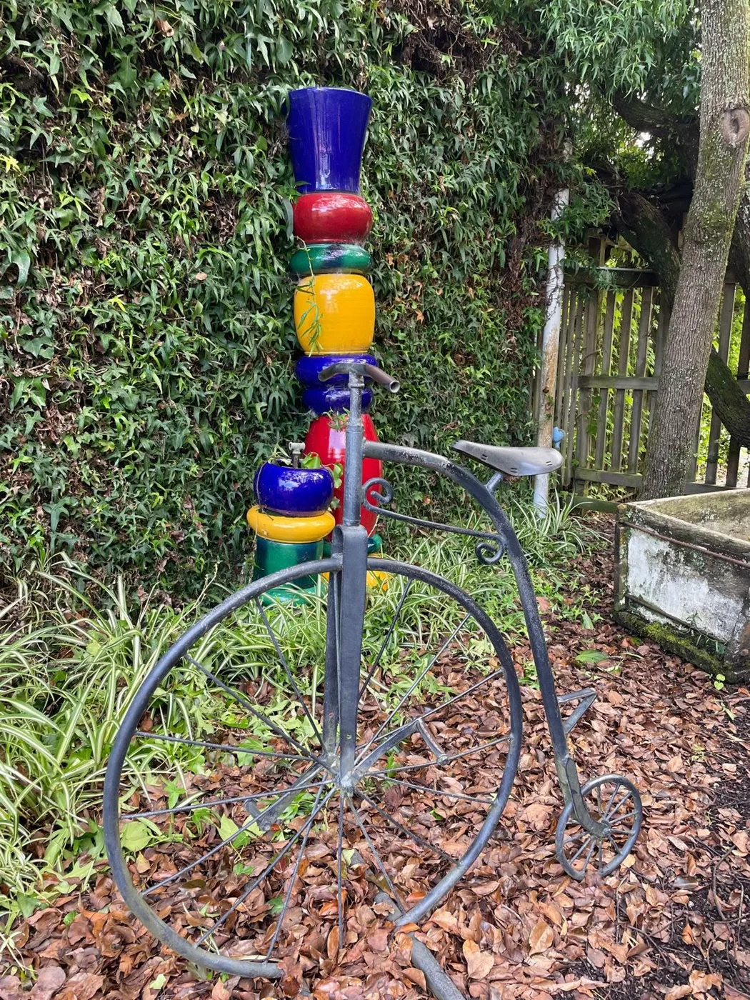 A penny farthing and a totem of stacked glazed pots in the garden