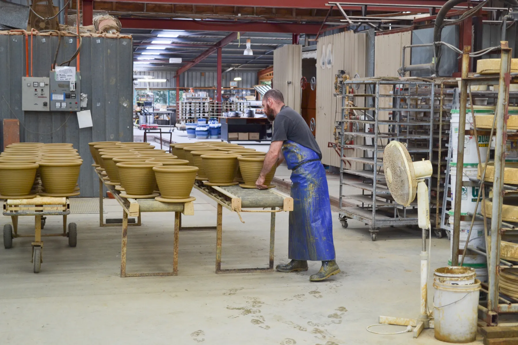 Moving freshly thrown pots along the roller racks