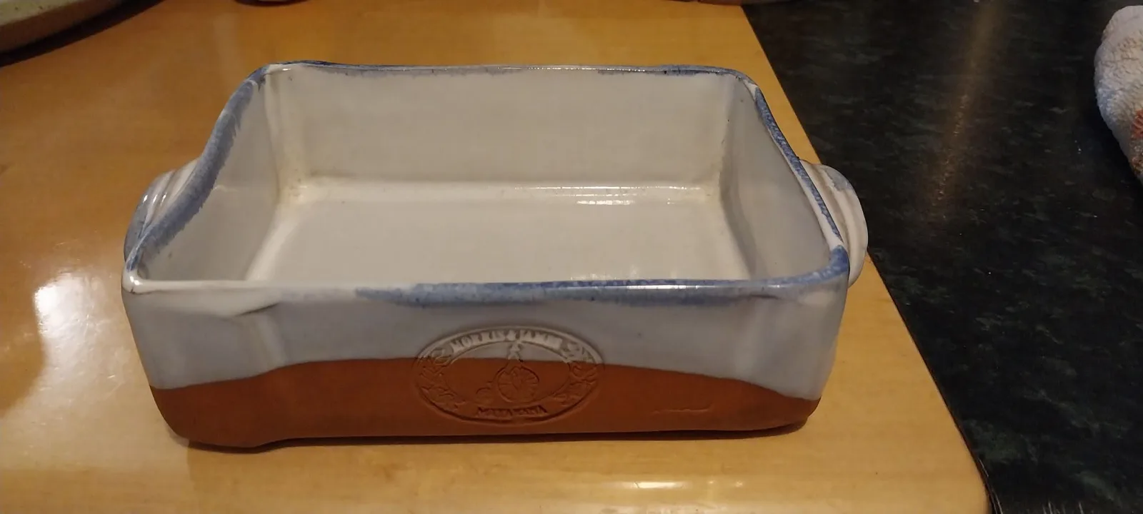 A Farmhouse baking dish with white glaze, a blue rim, a terracotta base and the Morris & James stamp