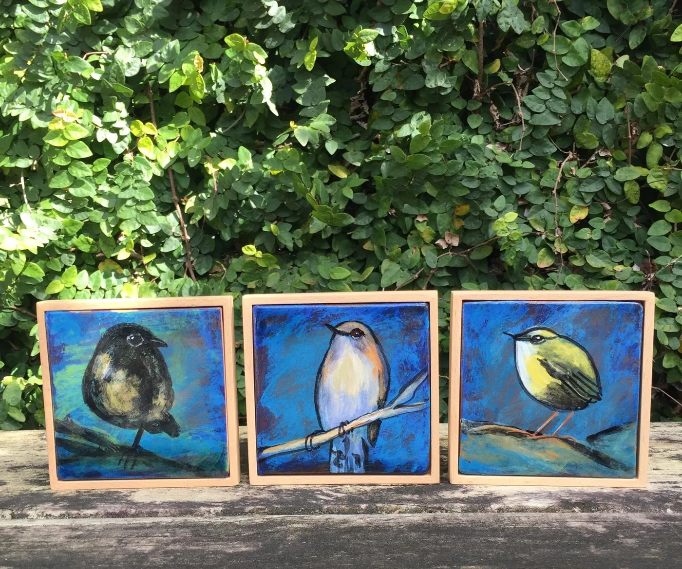 Three framed ceramic icons hand-painted with native birds on deep blue backgrounds