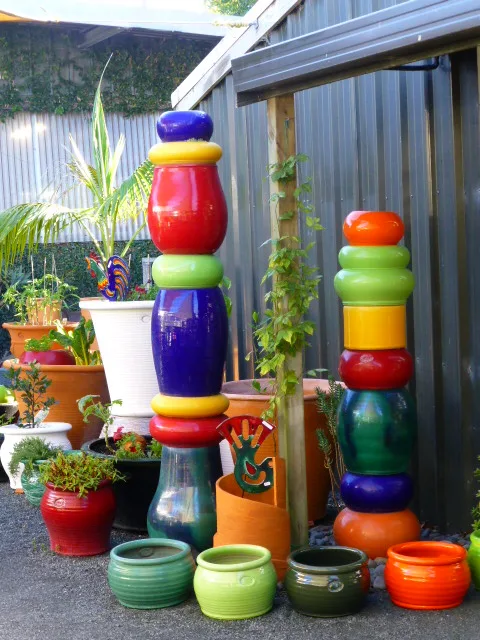 Two tall columns of stacked pots and rings in red, blue, yellow, green and orange, beside a row of glazed pots