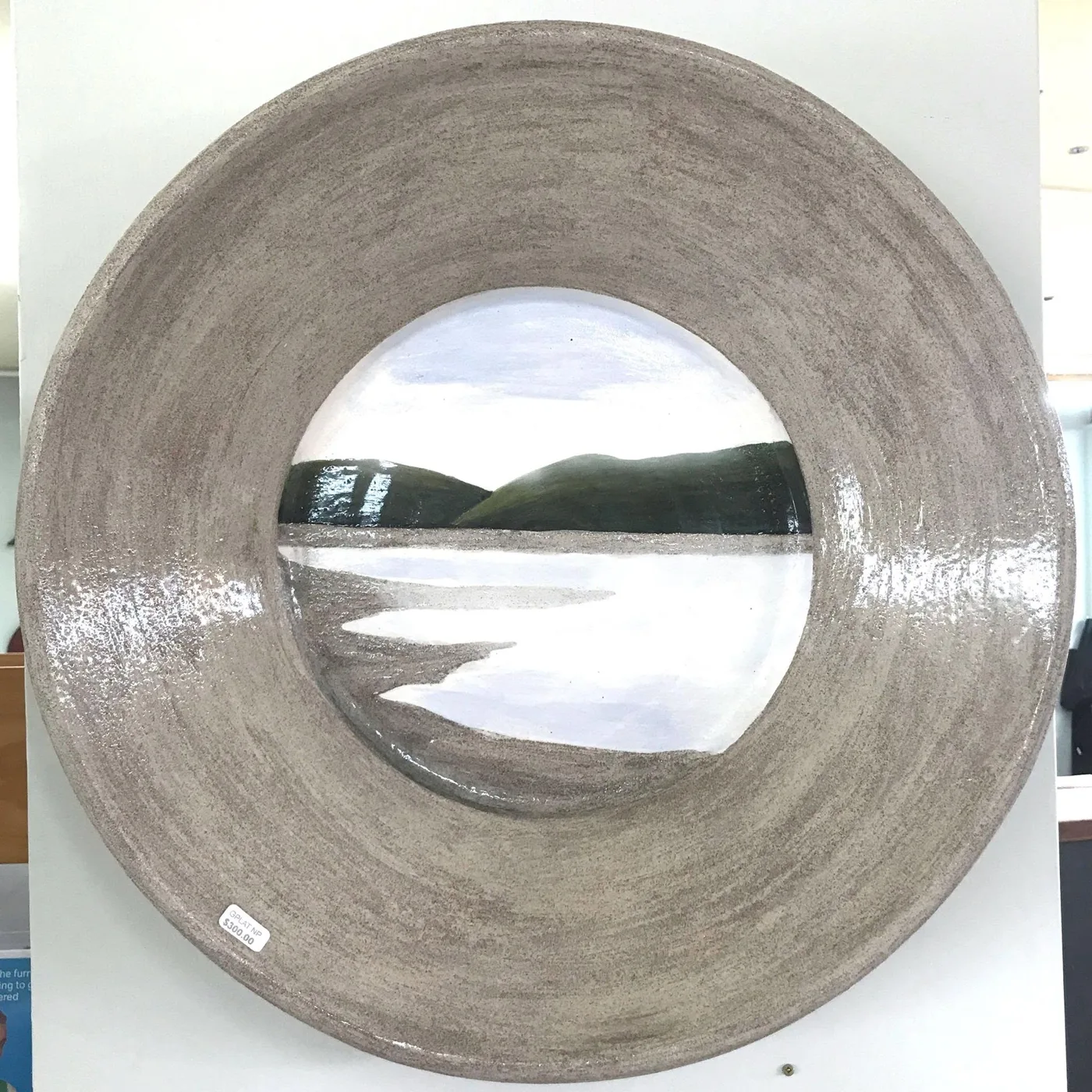 A Grand Platter with a speckled grey rim and a painted view of Omaha Beach, green hills and water