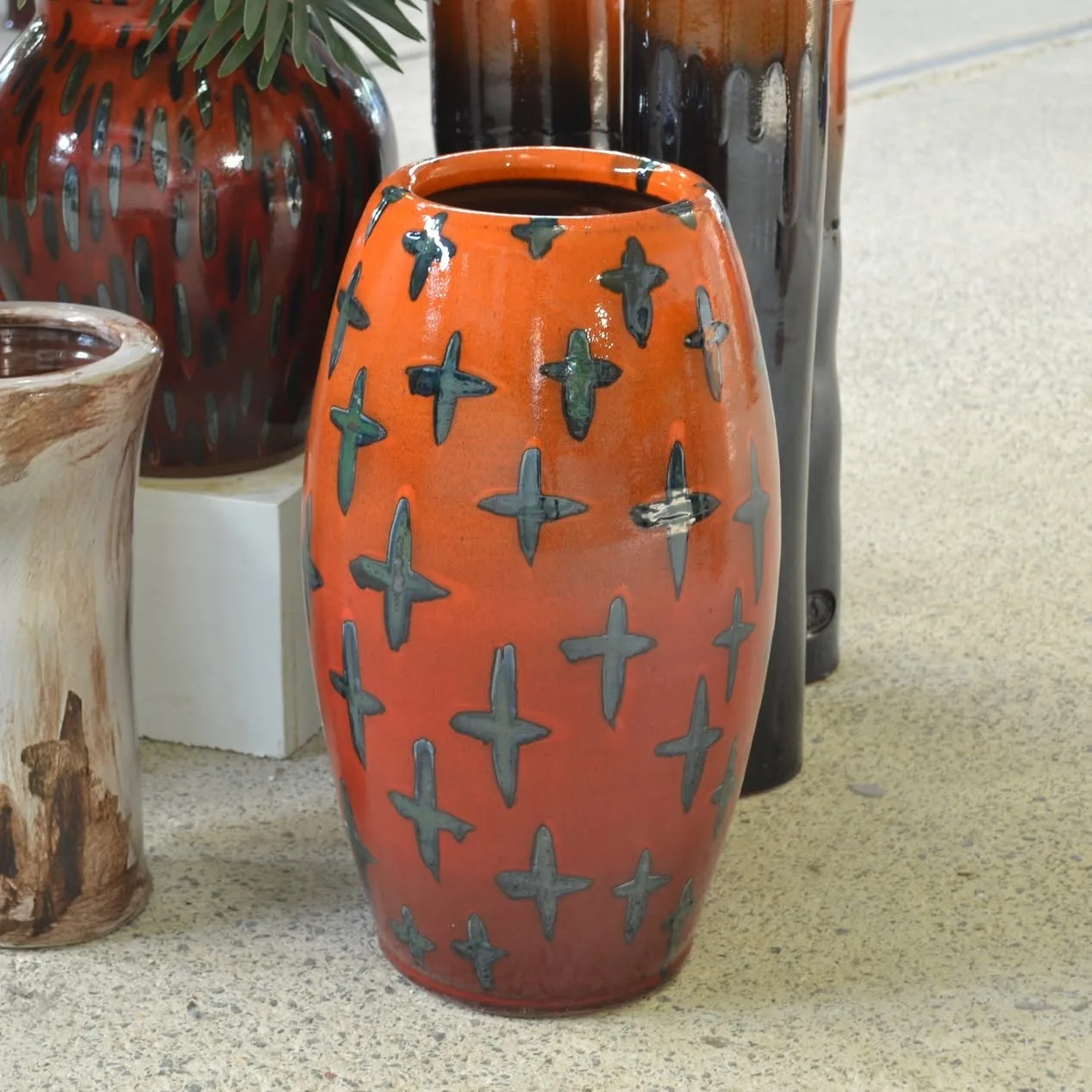 An orange pot decorated with dark crosses, on display in the showroom