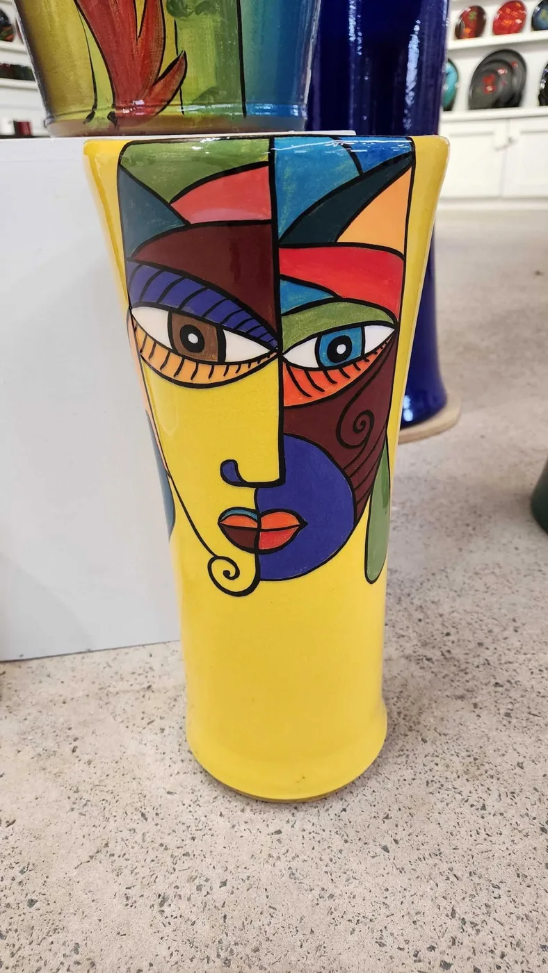 A yellow pot hand-painted with a Picasso-style face