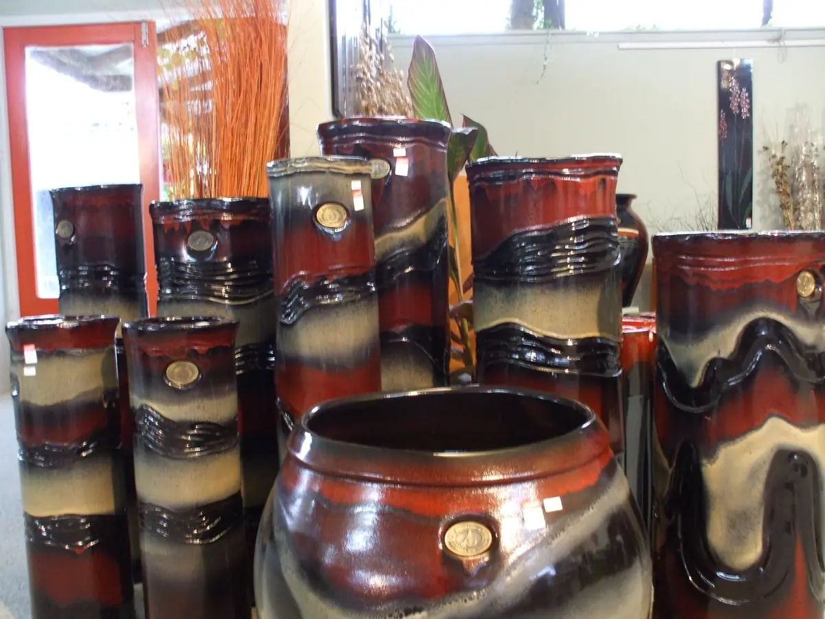 A showroom display of Froth pots and tall vases, banded in deep red, black and a creamy frothed glaze