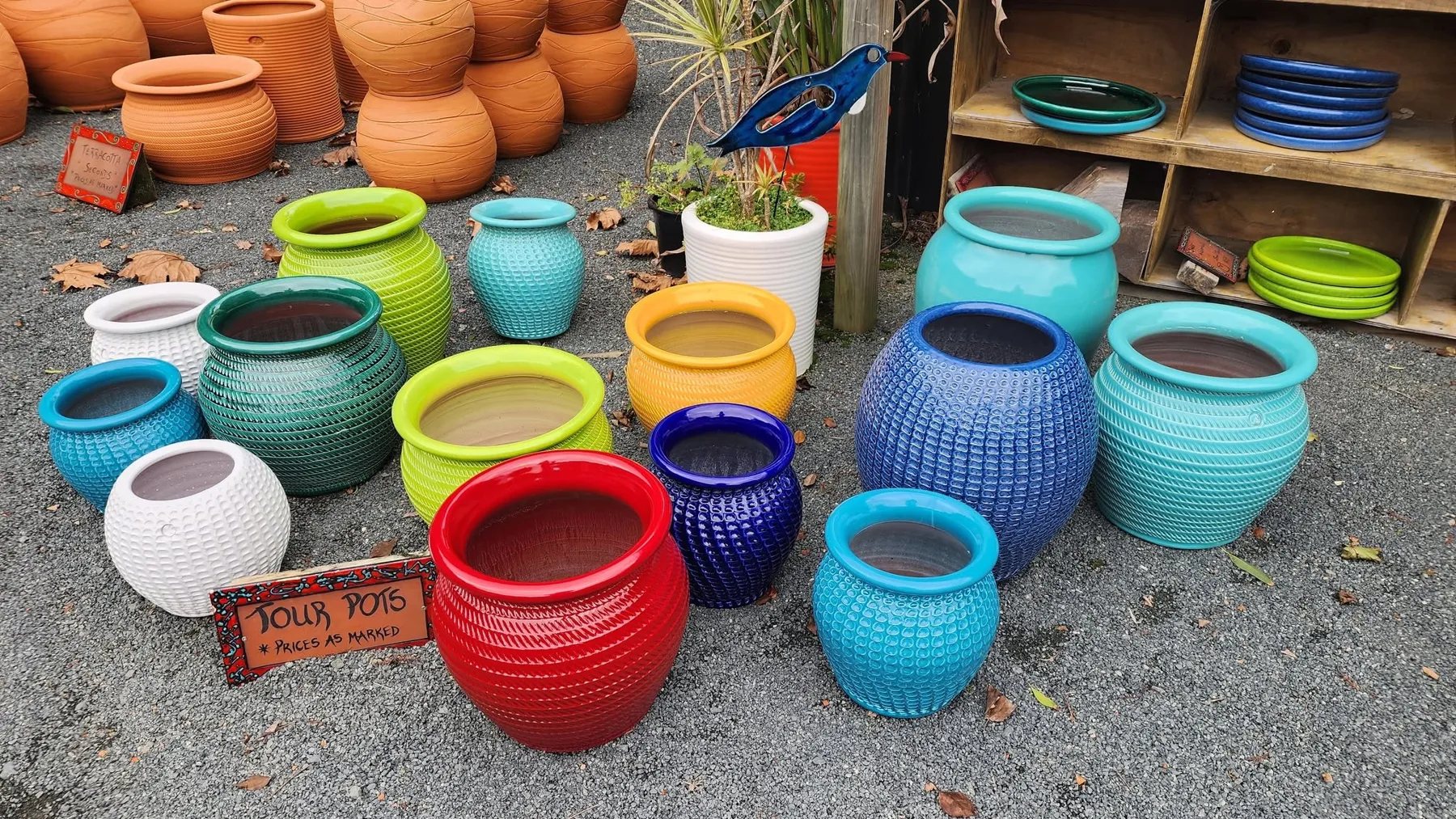 Tour Pots in bright glazes on the gravel, with a hand-painted Tour Pots sign